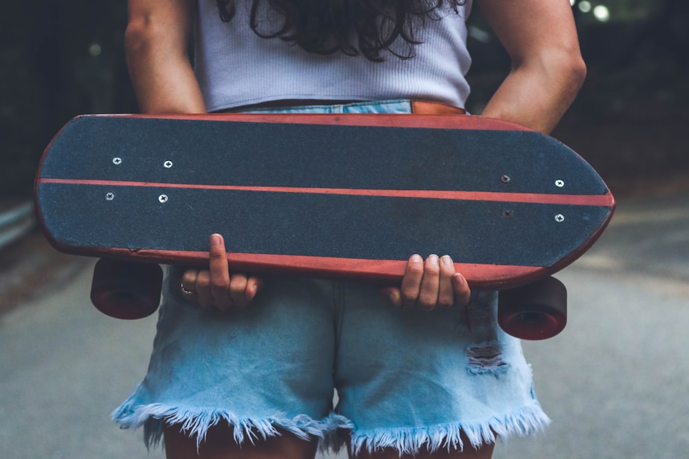 woman holding brown and black skateboard