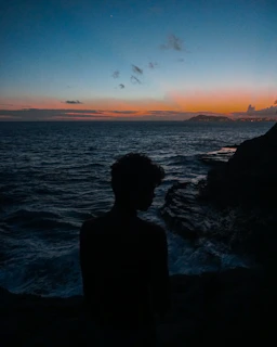 Mysterious silhouette of Joy Boy surrounded by ancient symbols and ocean waves.