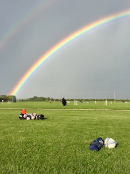 A cheerful mom packing a colorful sports bag with snacks, water bottles, and gear for her kids' soccer game on a sunny afternoon.