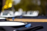 Close-up of a beautifully set dining table with dark gold tableware and deep blue napkins.
