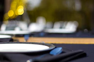 Artistic shot of a table setting with sable beige linens and black deep ceramic plates accented by gold cutlery.