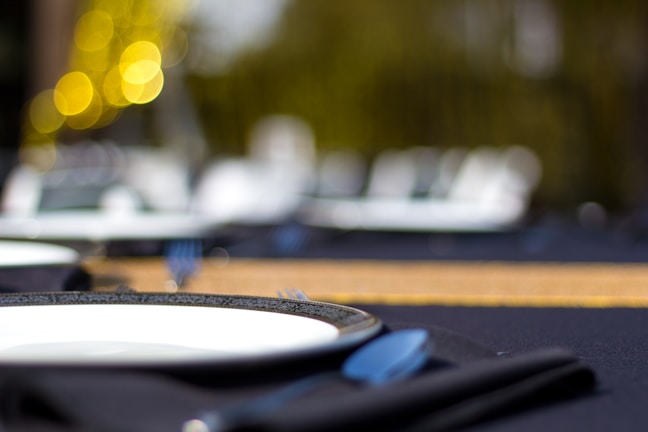 Close-up of a beautifully set dining table with dark gold tableware and deep blue napkins.