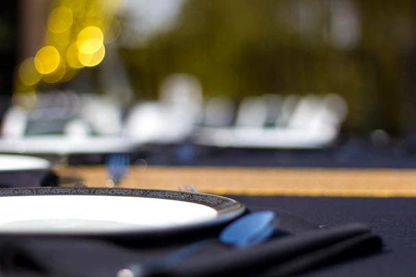 Close-up of a softly lit dining table featuring minimalist place settings and dark wood textures.