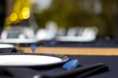 Close-up of elegant table settings featuring rustic plates and polished cutlery at a birthday celebration.
