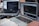 Two laptops displaying code are placed on a desk. One laptop is a Dell, and the other is a MacBook. Both screens show some programming code in a development environment. There is also a notebook with handwritten notes, a mouse, and a smartwatch on the table. A person is typing on the MacBook.