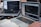 Two laptops displaying code are placed on a desk. One laptop is a Dell, and the other is a MacBook. Both screens show some programming code in a development environment. There is also a notebook with handwritten notes, a mouse, and a smartwatch on the table. A person is typing on the MacBook.