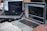 Two laptops displaying code are placed on a desk. One laptop is a Dell, and the other is a MacBook. Both screens show some programming code in a development environment. There is also a notebook with handwritten notes, a mouse, and a smartwatch on the table. A person is typing on the MacBook.