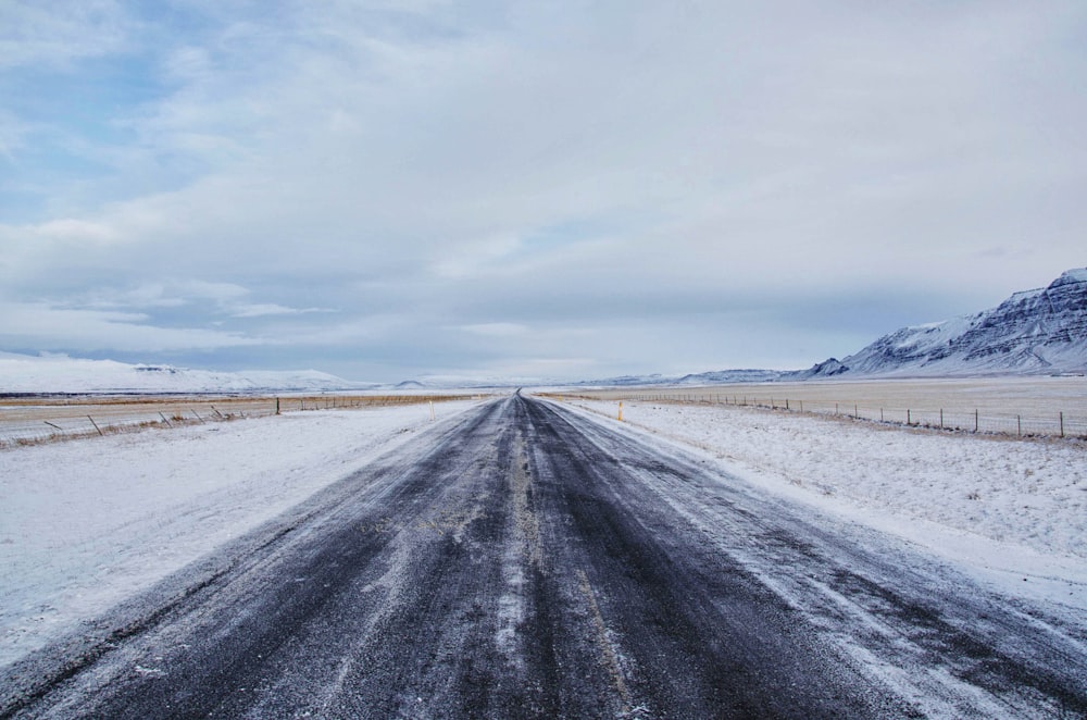 gray asphalt road surrounded by snow