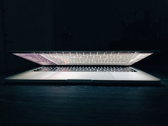 A sleek laptop displaying lines of code with a softkai logo glowing subtly on the screen.