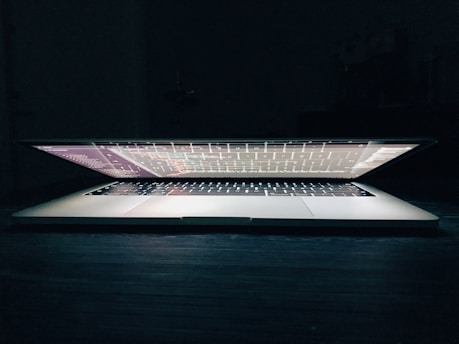 A sleek laptop displaying lines of code with a softkai logo glowing subtly on the screen.