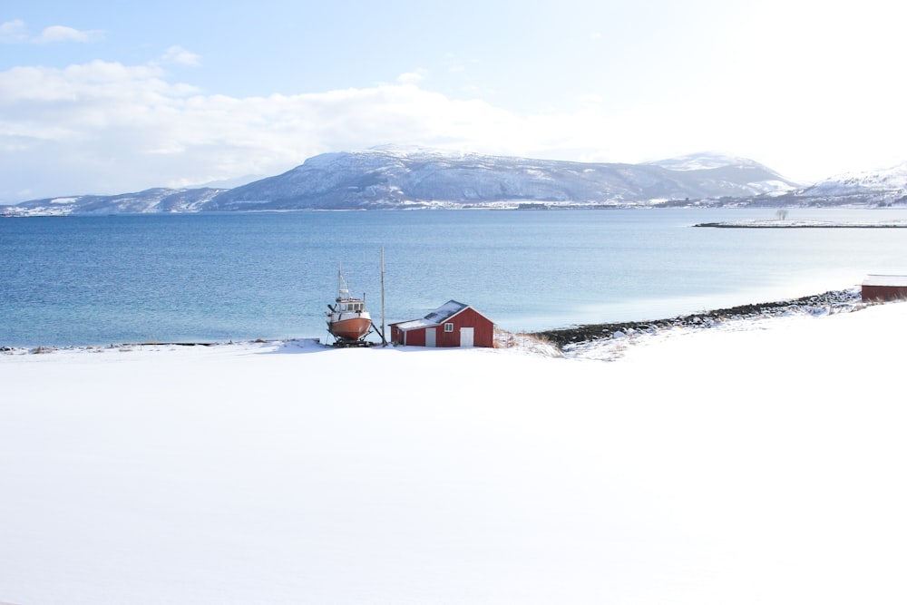 red house between sea and snow covered sand