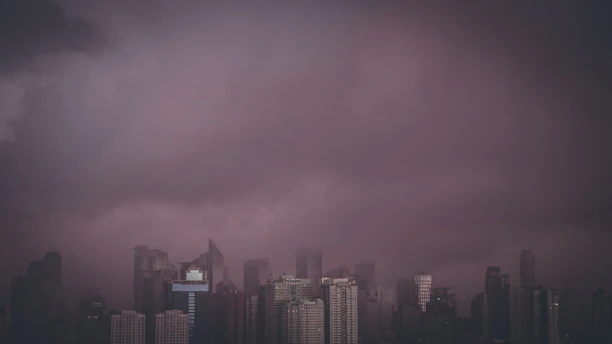 A dramatic skyline showing the silhouettes of global landmarks like the UN headquarters and skyscrapers under a stormy sunset, symbolizing global tensions.