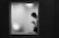 A blurred silhouette of a person standing behind a frosted window, suggesting mystery and privacy. The figure appears to be engaging with something in their hands, possibly a smartphone.