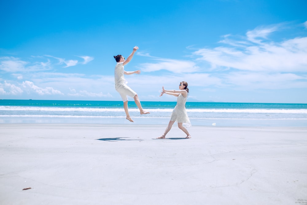 man and woman playing on white sand near seashore during daytime