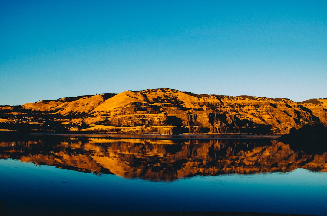 brown land on body of water under blue sky