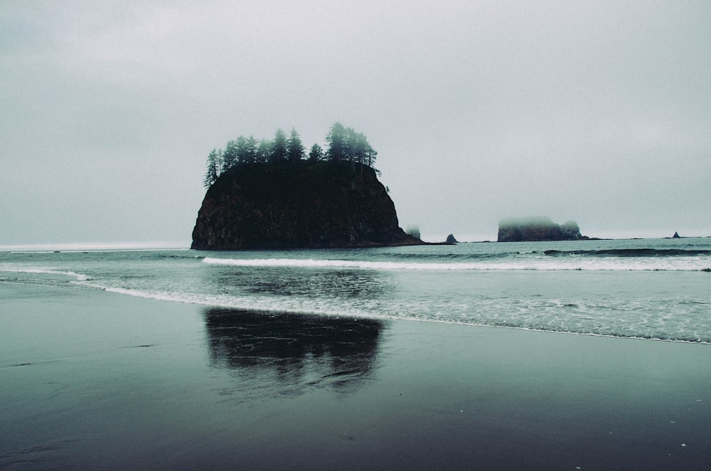 islet on body of water under cloudy sky