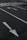 A parking lot with white directional arrows on the asphalt, a pedestrian crosswalk, and part of a bicycle lying on the ground with a glimpse of a person's legs.