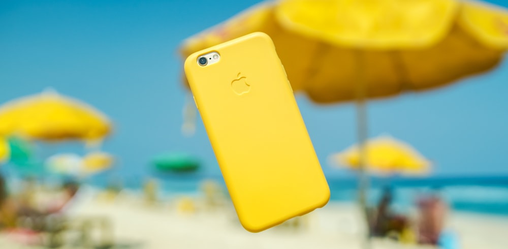 iPhone con cover gialla appesa all'aria