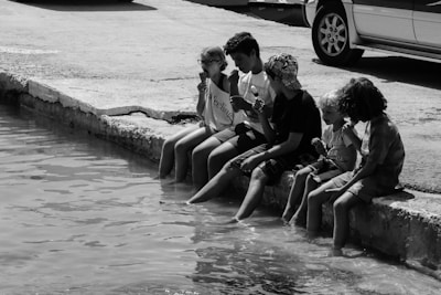 Kids laughing while dipping fresh fruit into sweet crema at a lively outdoor setting.