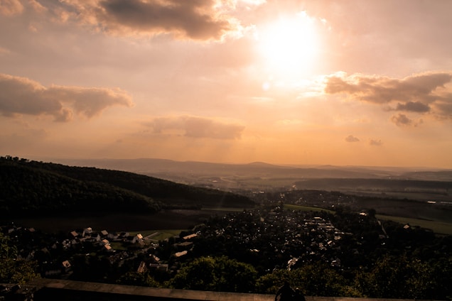 A scenic valley at sunrise, with soft golden light illuminating a peaceful town nestled among rolling hills.