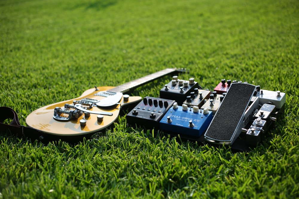 茶色のレスポールスタイルのエレキギターがギターエフェクトの近くの草の上に