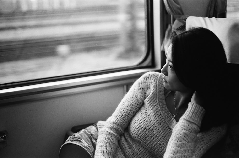 grayscale photo of woman leaning on vehicle seat during daytime