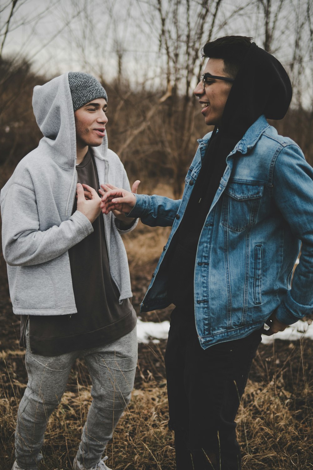 two man talking while laughing on brown grass