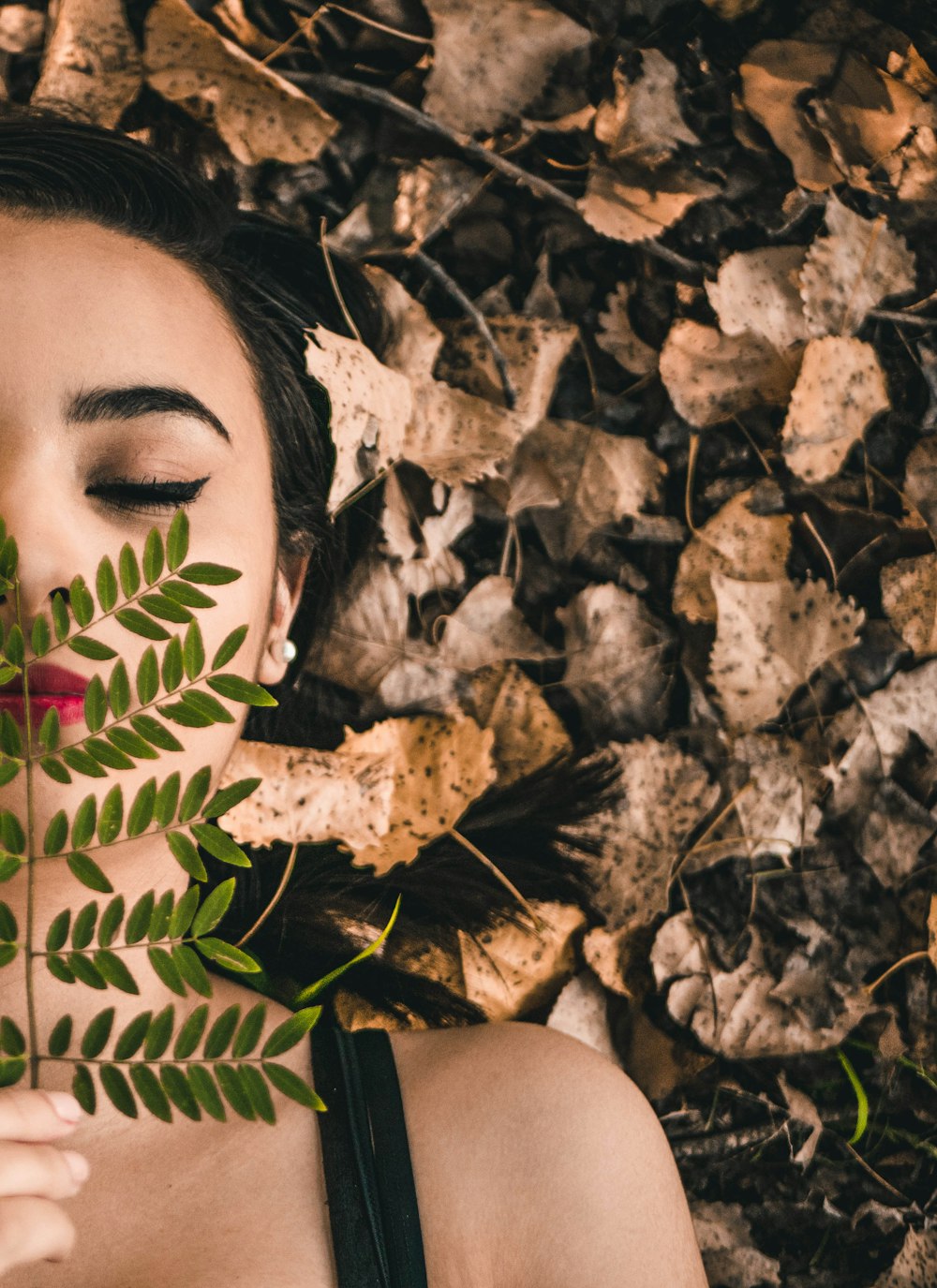 persona sosteniendo hojas cubriendo los labios