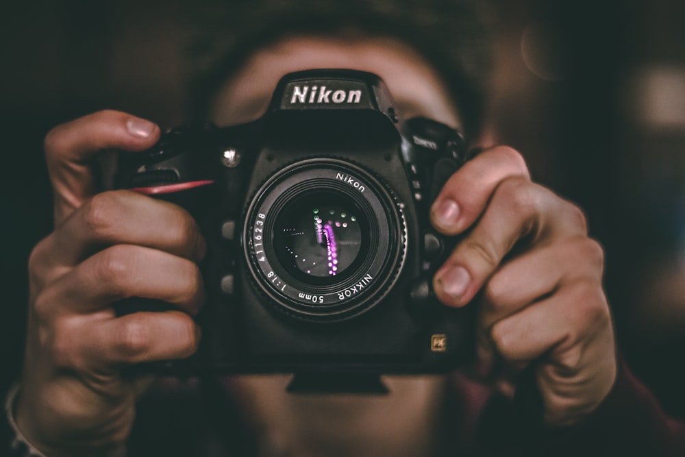 Das Gesicht einer Person wird von einer Nikon DSLR-Kamera verdeckt