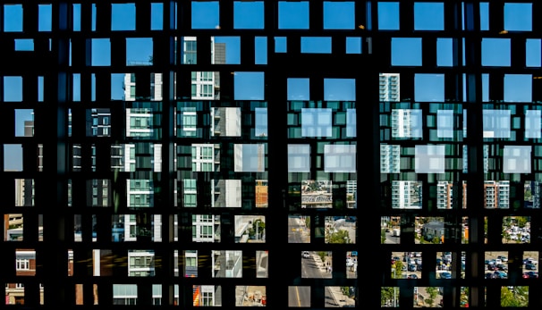 Abstract digital grid overlaying a cityscape, glowing softly with neon blue and white accents.