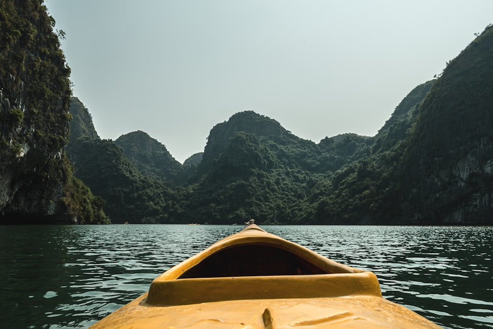 bateau marron dans l’eau entouré de montagnes