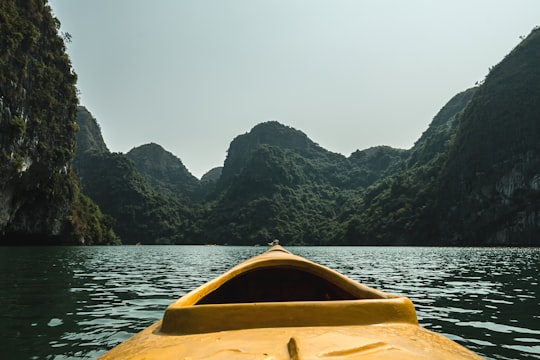 brown boat in the water surrounded by mountains in Ha Long Bay Vietnam