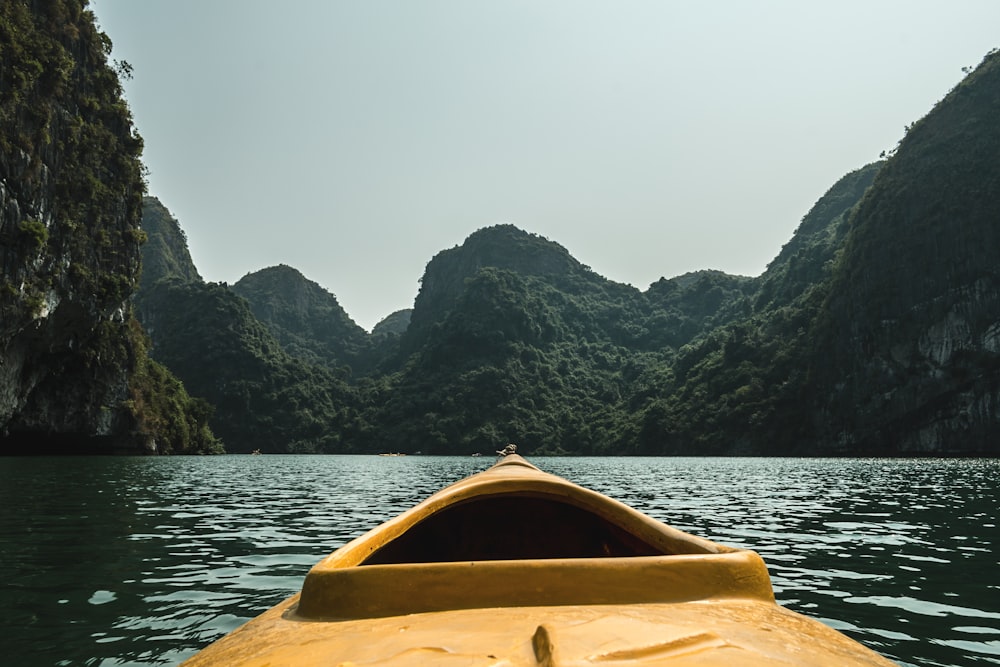 brown boat in the water surrounded by mountains