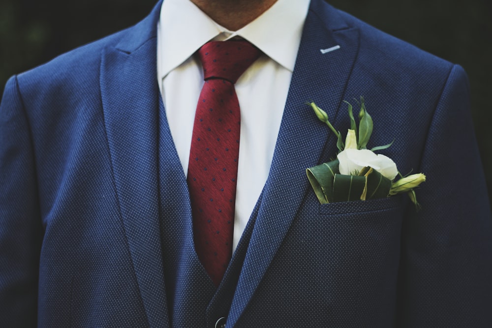 persona che indossa giacca blu e cravatta rossa