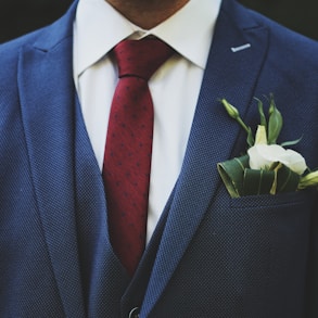 person wearing blue suit jacket and red necktie