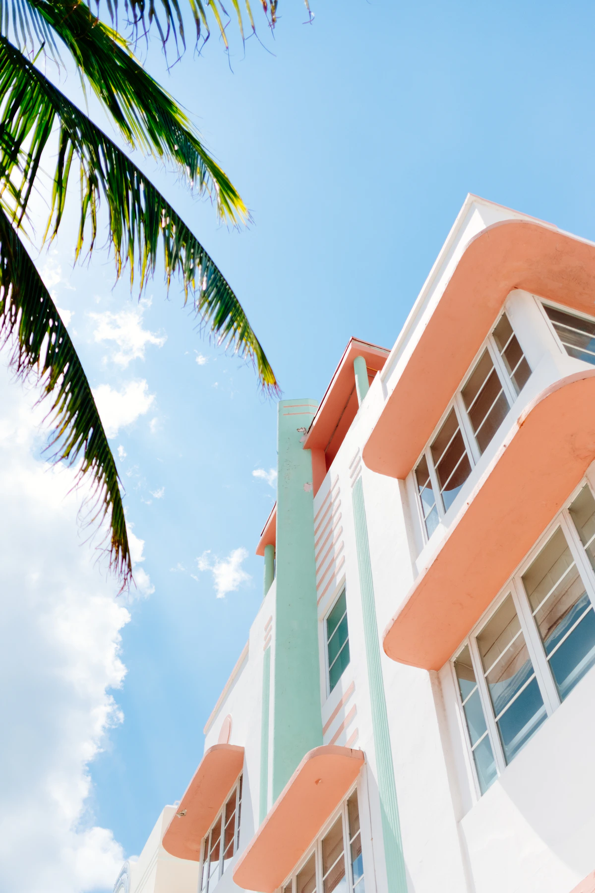 A peach-and-white Art Deco building framed by a palm tree in Miami Beach