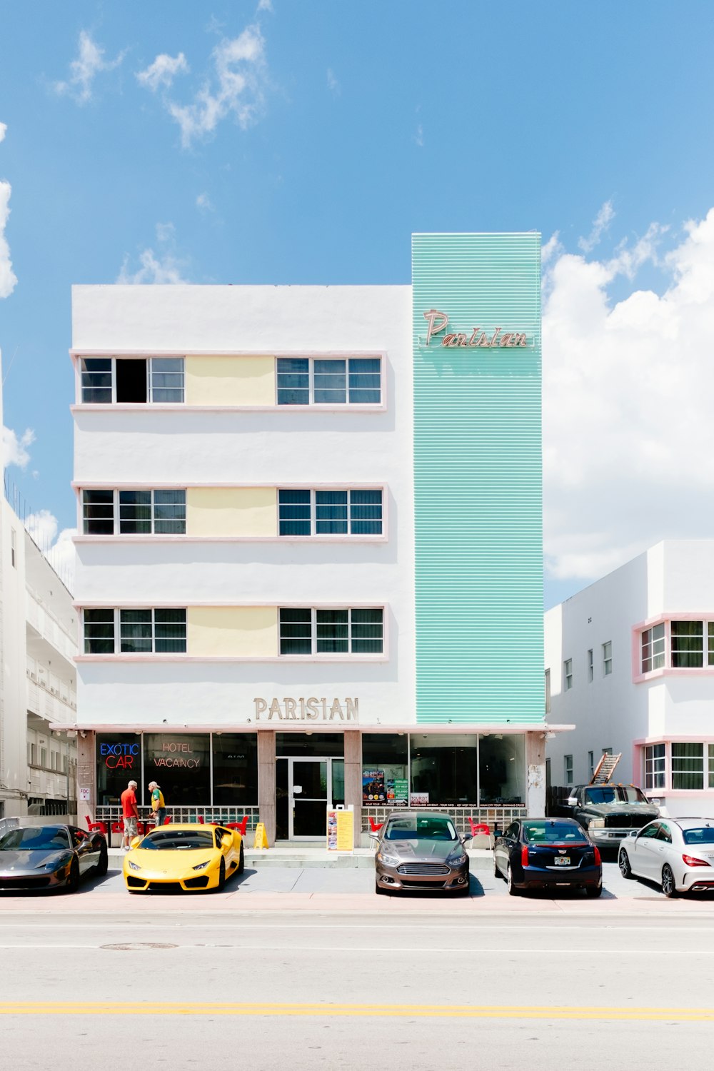 assorted-color cars beside white Parisian building under blue sky at daytime