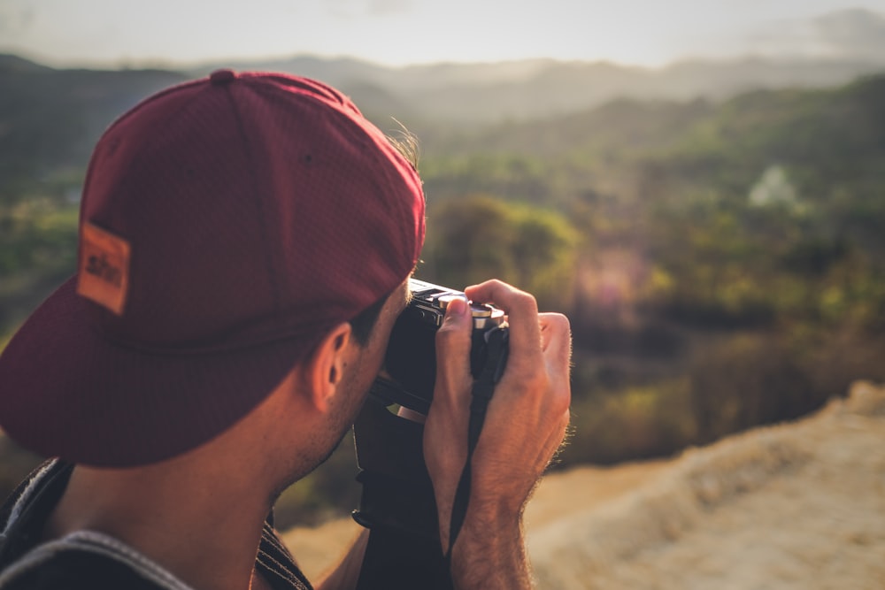 homme en casquette cintrée rouge prenant une photo