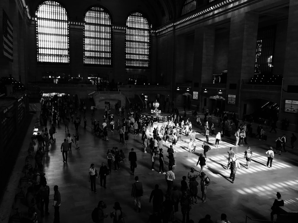 grayscale photo of people walking inside the building