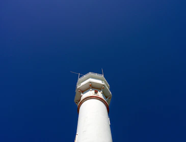 Abstract minimalist design of a lighthouse integrated with financial graphs.