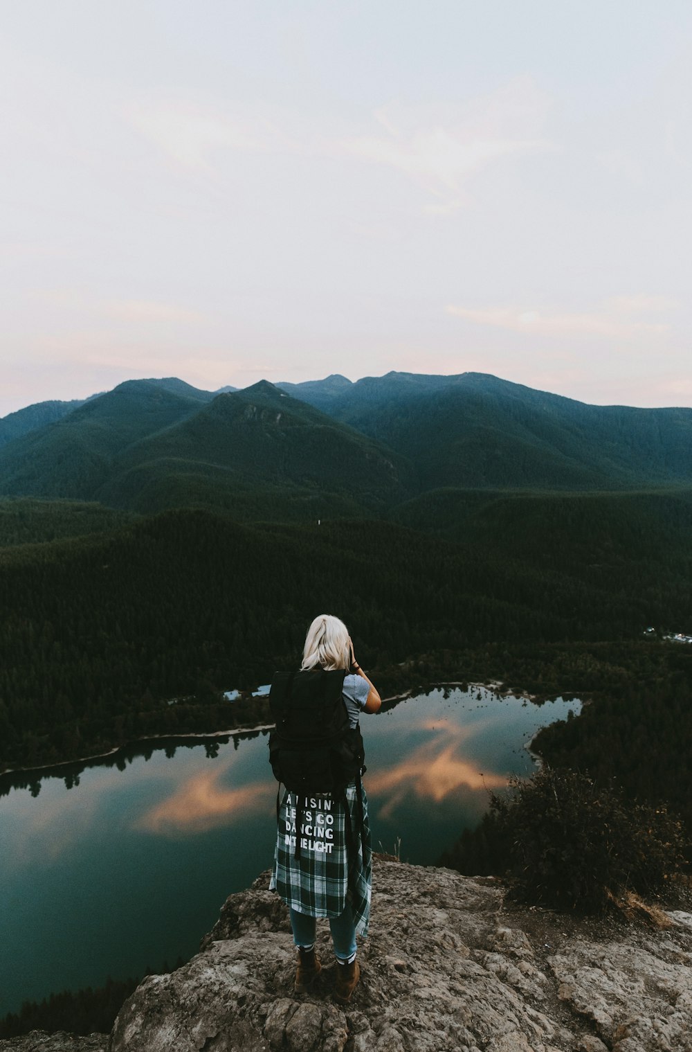 Donna in piedi sulla scogliera che scatta foto di montagna
