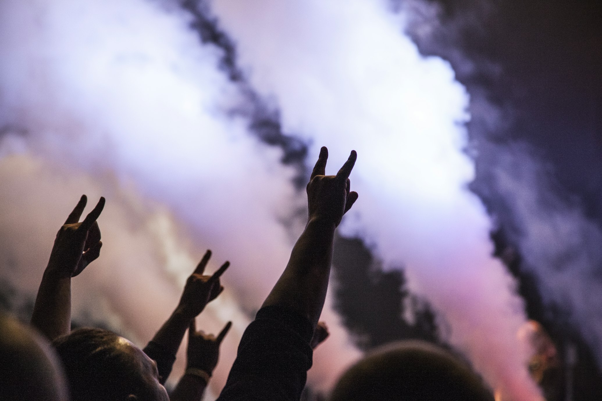 people with hands up at rock concert