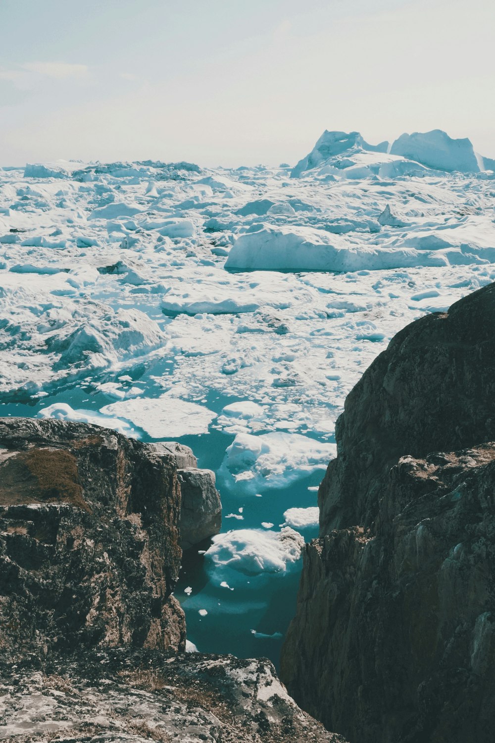 two brown rocks surrounded by ice blocks under white sky during daytime