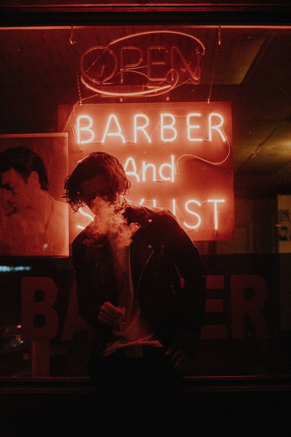 man smoking in front of barber neon light signage