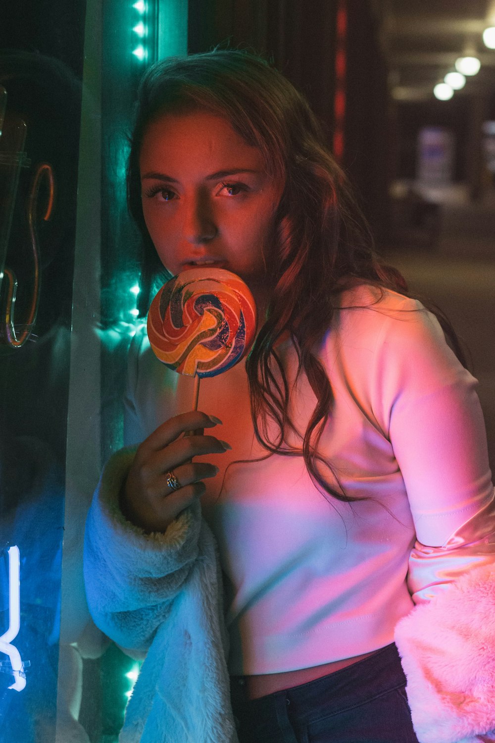 woman wearing white top holding lollipop