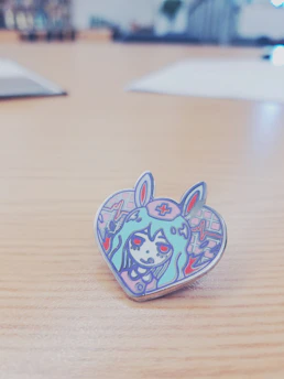 Stylish white enamel pin with a bold, artistic symbol