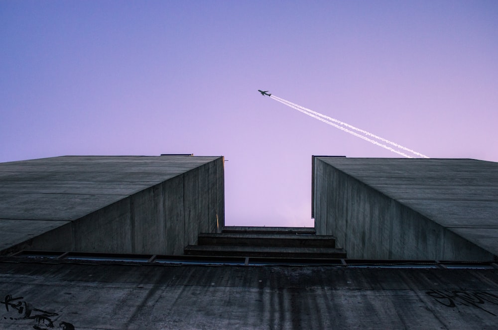 low angle photography of airplane flying over building