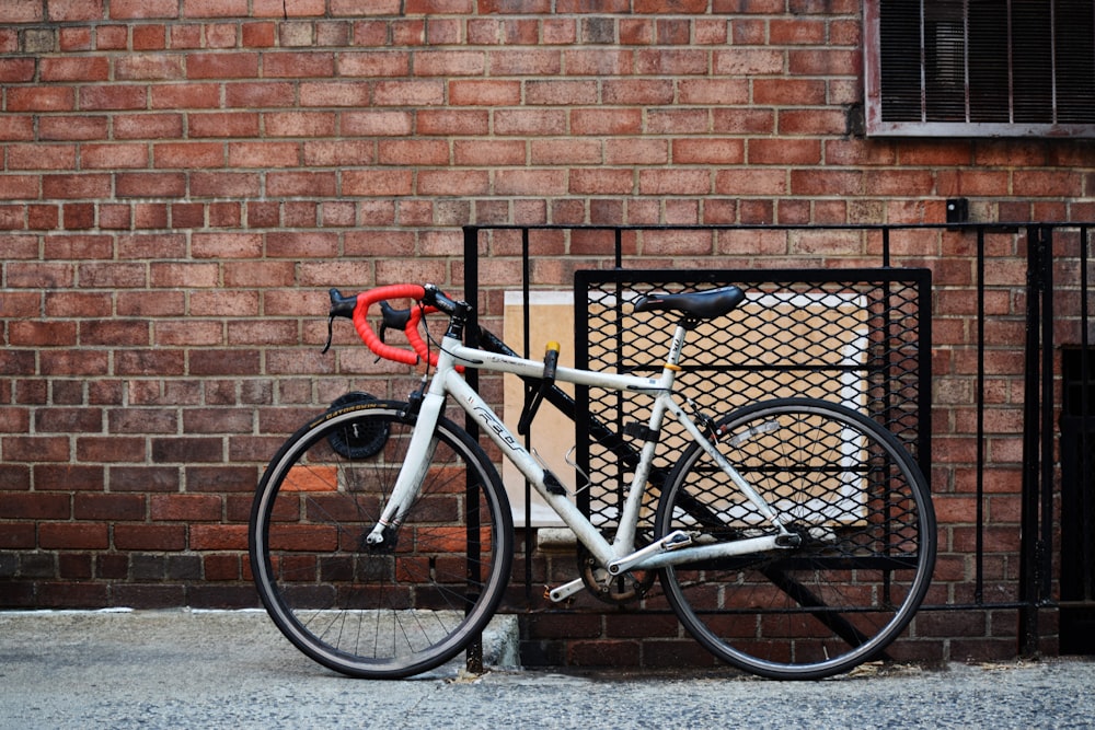 white road bike parked beside the gate