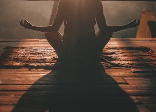 woman doing yoga meditation on brown parquet flooring