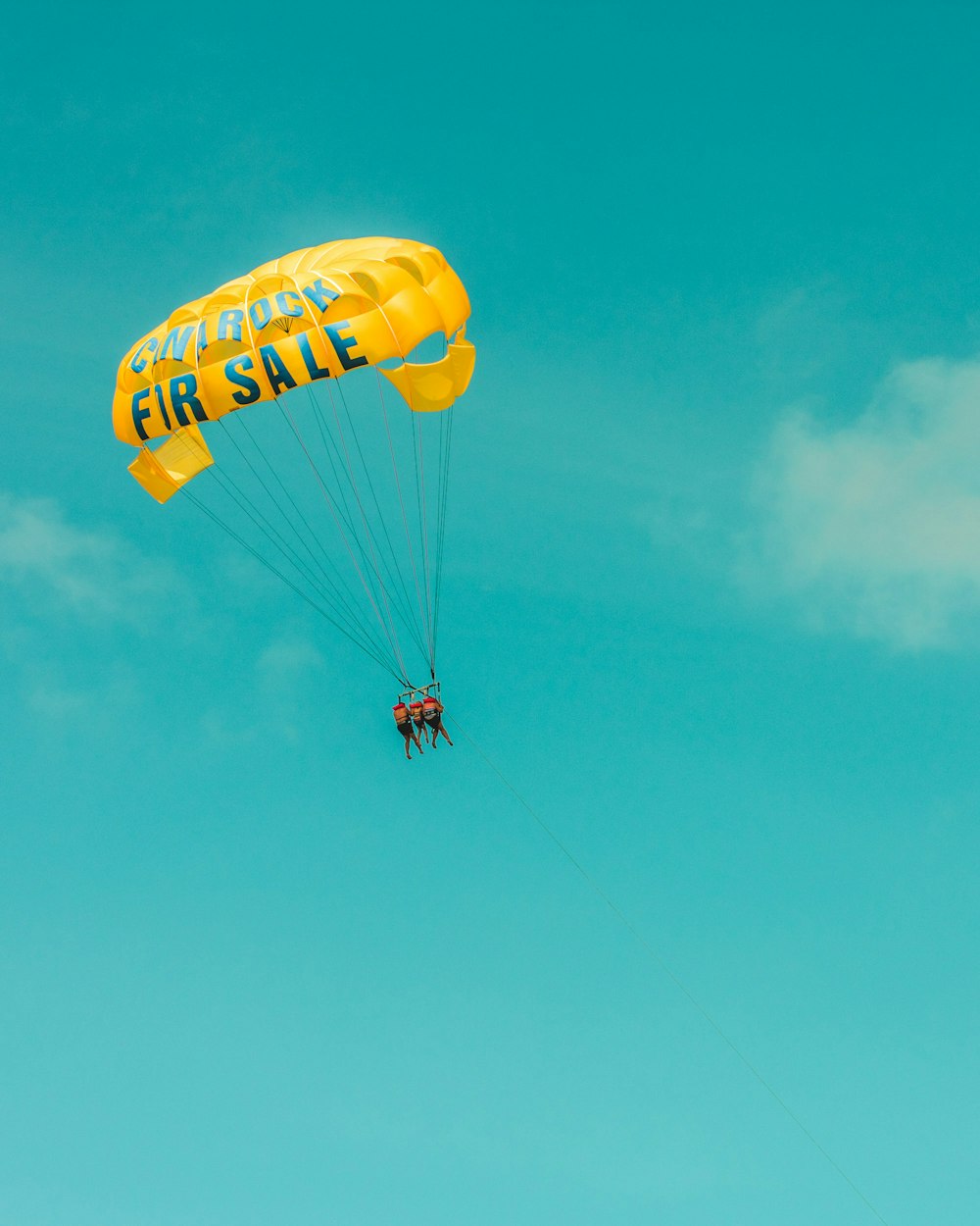 three person on yellow parachute